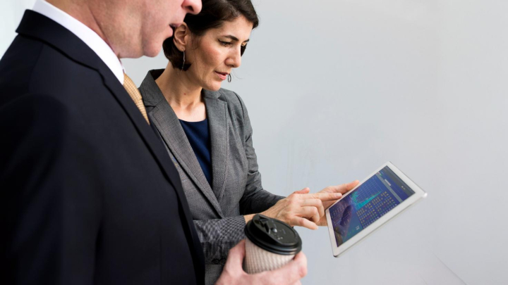 Dos personas trabajas sobre la pantalla de una tablet.