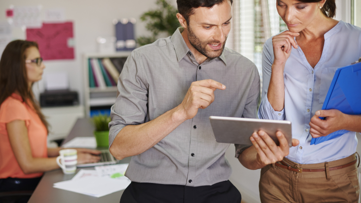 Una pareja de jóvenes administradores de fincas trabajan juntos con medios digitales.