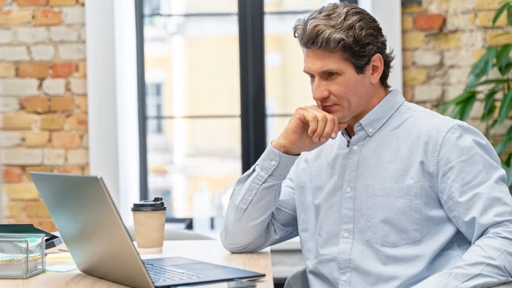 Un administrador de fincas trabaja la frente a una pantalla de un ordenador portátil.