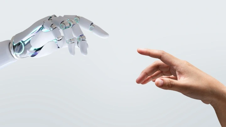 Gesfincas ha iniciado una gira por varios Colegios de Administradores de Fincas para presentar la gran novedad de esta temporada: la inteligencia artificial integrada. Ya no se trata de añadir ChatGPT para escribir textos, sino de transformar de raíz la forma en la que se interactúa con el software, se ejecutan acciones complejas y se accede a la información desde cualquier lugar. Esta nueva generación de herramientas quiere cambiar las reglas del juego en los despachos. Una mano robótica prácticamente toca una mano humana en una imagen que recuerda el famoso cuadro "La creación de Adán" de Miguel Ángel.
