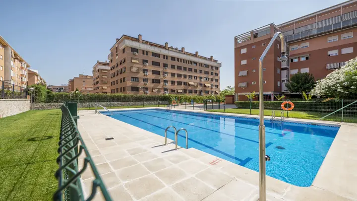 piscina-de-una-urbanizacion-con-escaleras-metalicas-y-jardines-con-cesped