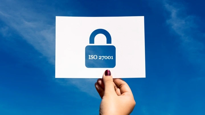 Una mano de mujer sujeta una cartel con una certificación ISO 27001