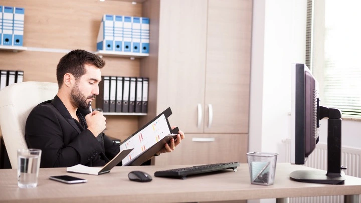 Administrador revisando documentación y datos en una tablet desde su despacho, en un entorno de trabajo profesional relacionado con la gestión administrativa.