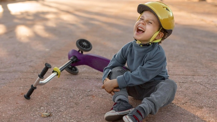 Niño con casco tras caer de un patinete, representando un accidente en espacios comunes y la importancia de la responsabilidad y la prevención.